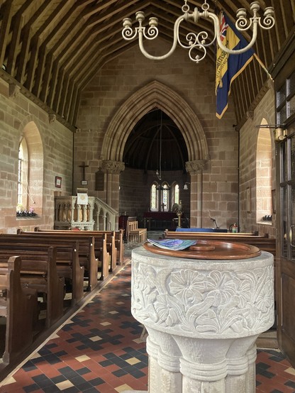 Inside St Michael, font, sandstone walls and arch, wooden beam roof