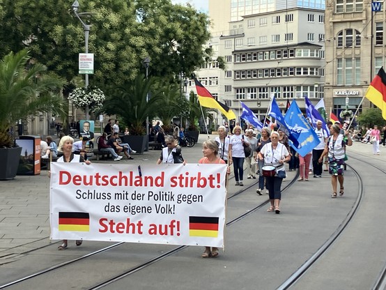 Foto aus der Erfurter Altstadt: darauf eine handvoll demonstrierender Altnazis mit Deutschlandfahnen. Fronttranspi: 