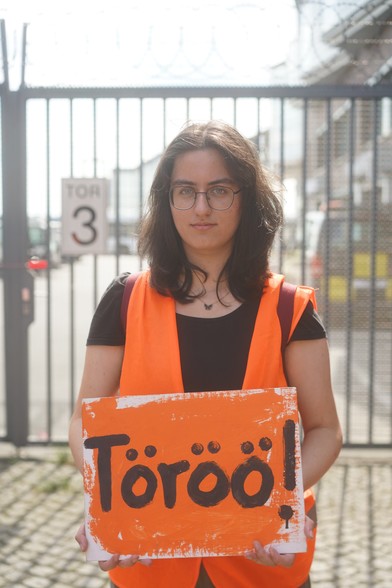 Person hält vor einem Tor ein Schild hoch auf dem steht: Töröö!