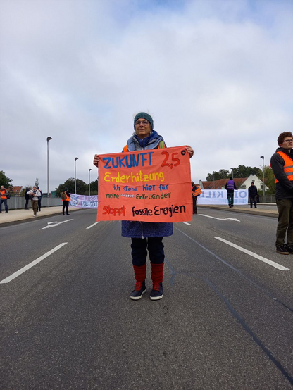 Eine ältere Frau die ein Banner hält mit: 