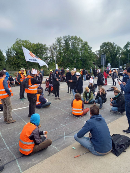 Straßenschah mit Menschen, die im Protest sind. Auf deren Köpfen die Symbole der Figuren