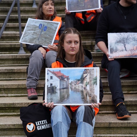 Menschen auf der Rathaus Treppe mit Bildern von Auswirkungen der Klimakrise.